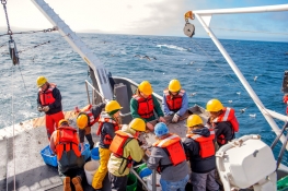group of students wearing safety gear on a vessel doing research